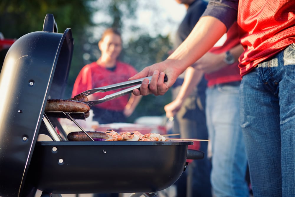 Men at a tailgate cooking BBQ.
