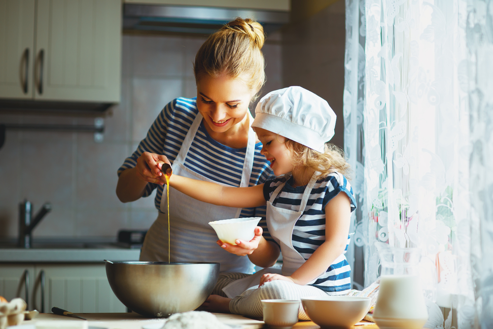 A happy mother and daughter cooking together in the kitchen