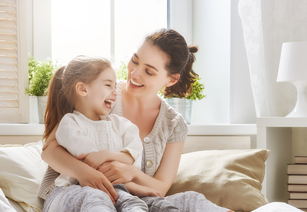 A laughing young mother holding her laughing happy young daughter