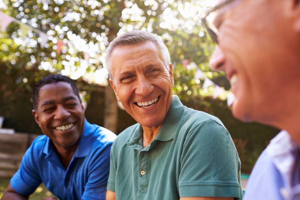 Three male friends chatting at an outdoor gathering.
