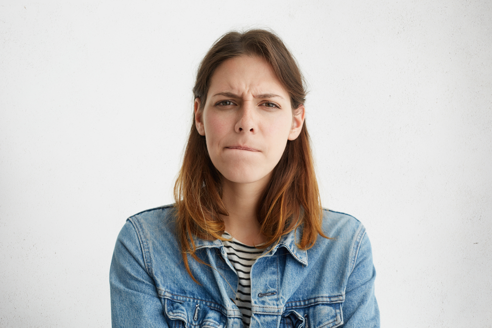 Woman biting her lip looking confused or annoyed
