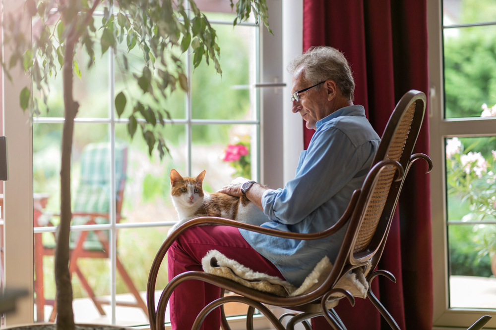 Senior man sitting in a rocking chair with his cat