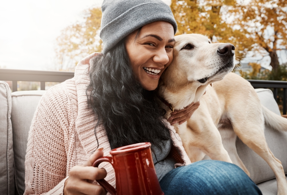 A happy woman enjoying a cup of coffee while spending time with her dog