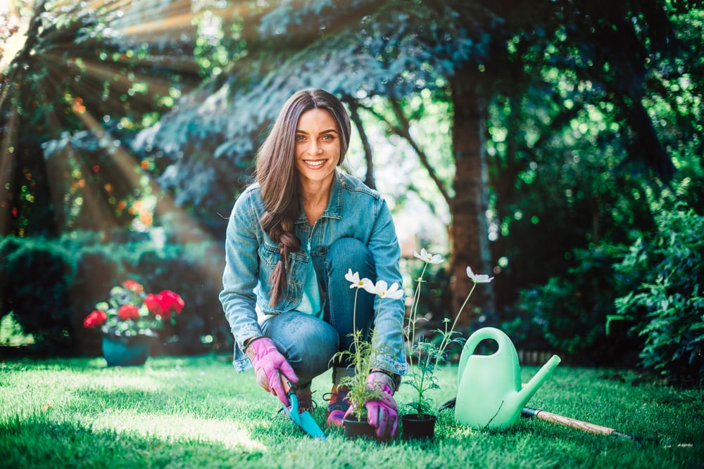 A young woman tending to her garden, with a water can to water her plants