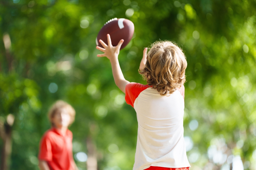 Kid playing football in the yard.