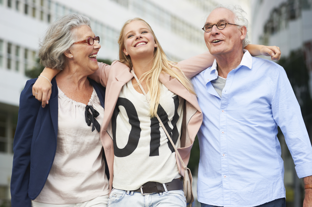 A teenage girl with her arms around her grandparents.