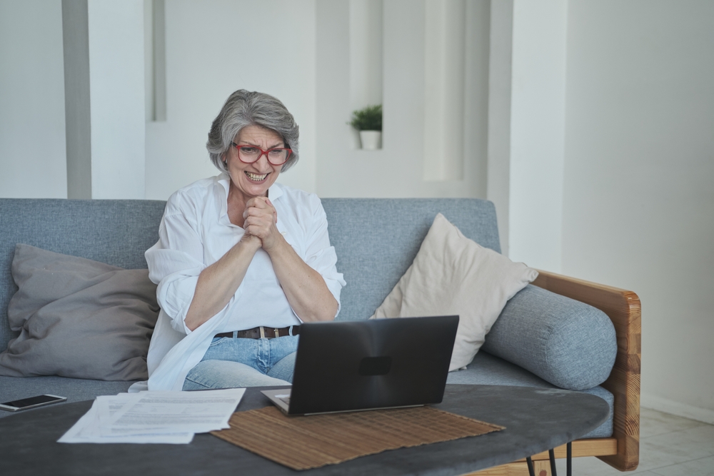 An excited, happy senior woman rejoicing at something she saw on her laptop in front of her