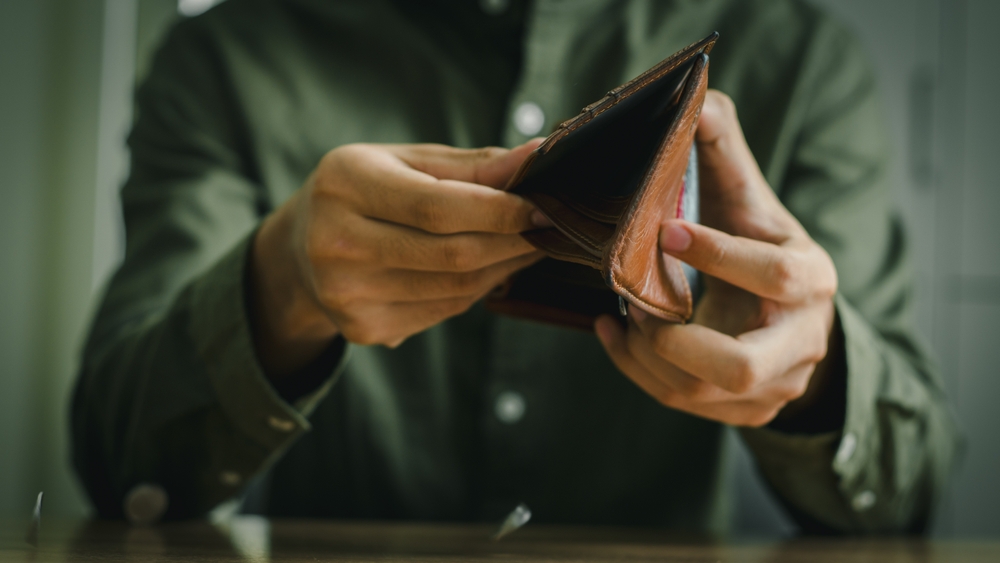 A bankrupt man turning an empty wallet upside down