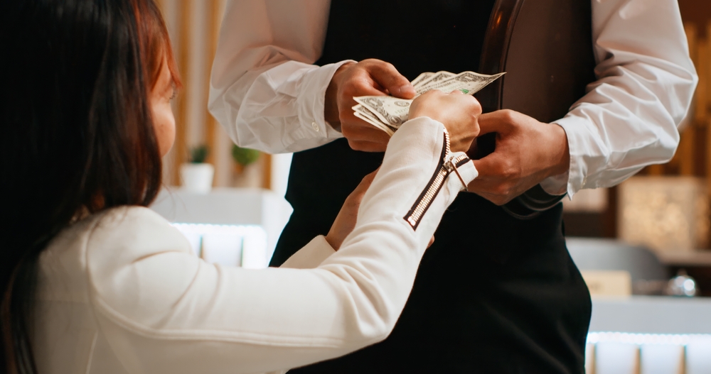 A woman paying her restaurant bill in cash.