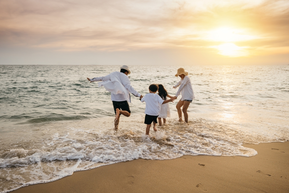 A happy family playing at the beach with both parents and two children