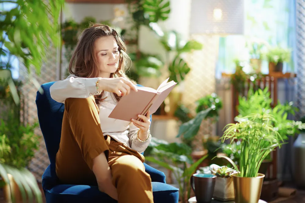 Woman reading sitting in front of plants