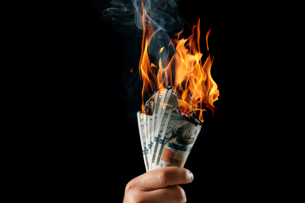 A man holding burning money.