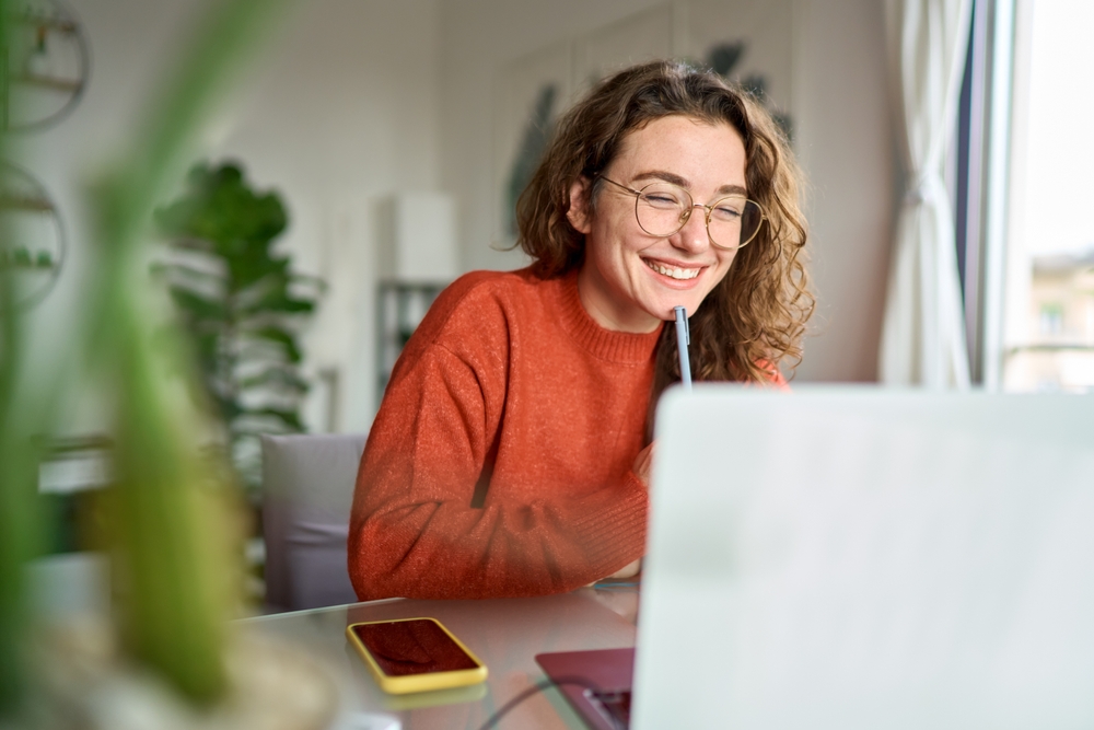 A happy young woman looking at her laptop and smiling