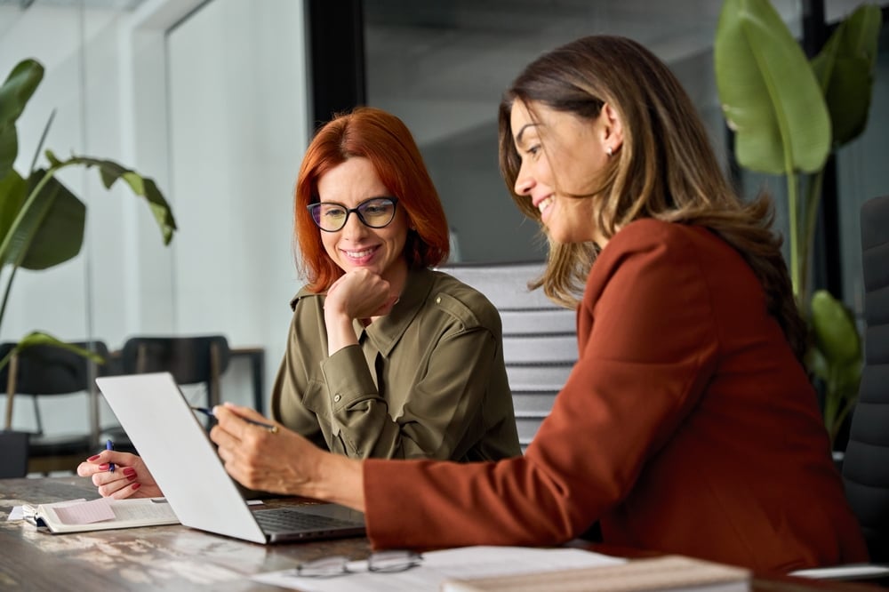 Two happy and busy young businesswomen working together