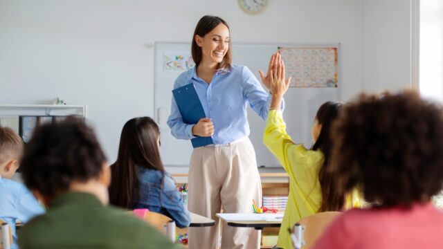 Cheerful female teacher, giving a high five to her student.