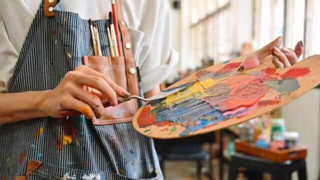 Artist holds paint palette, filled with vibrant colors.