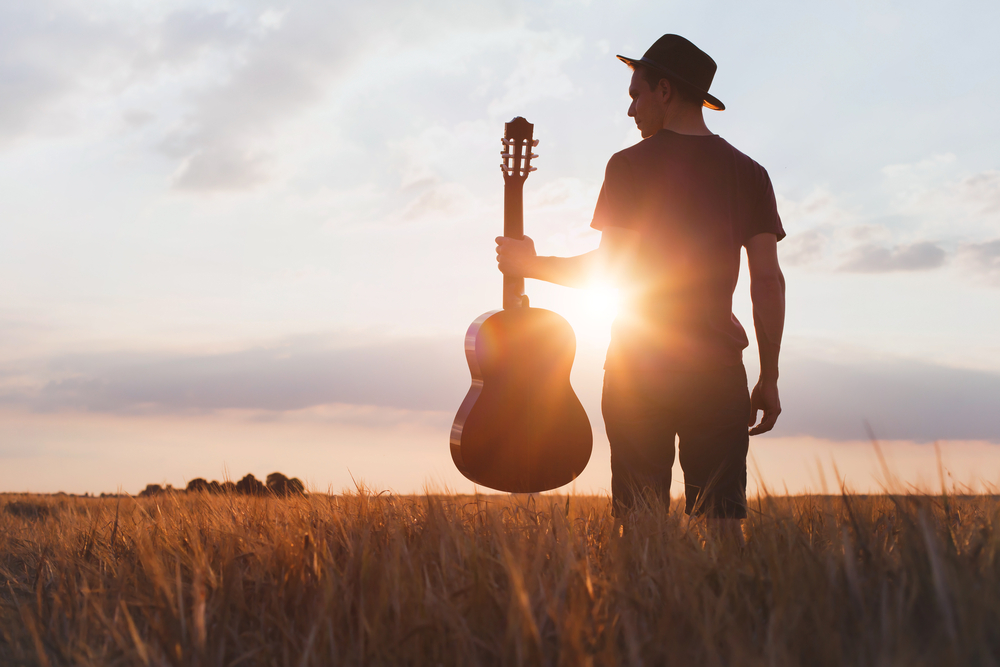 Silhouette of a musician standing and holding a guitar