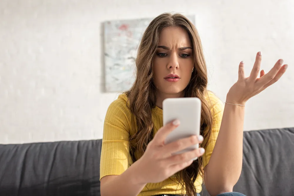 Woman looking at her phone confused.