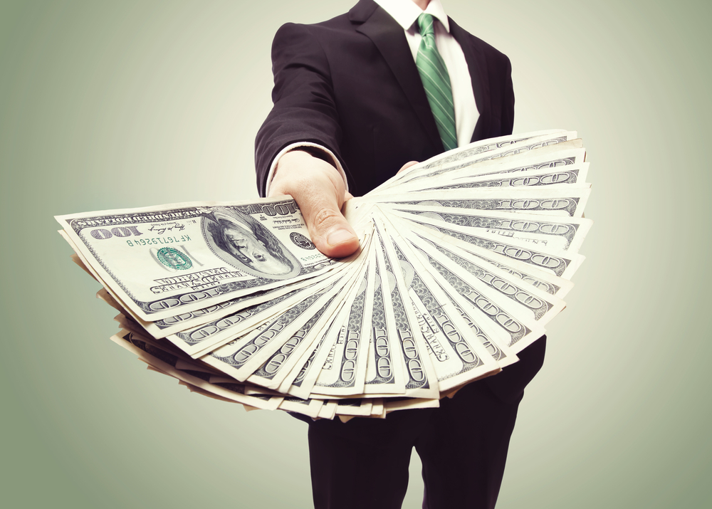 Many holding out a wad of money, American dollar bills