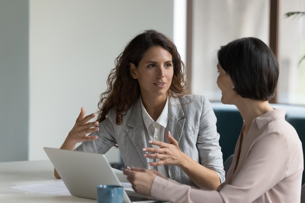 Two business women, female colleagues having a discussion at work
