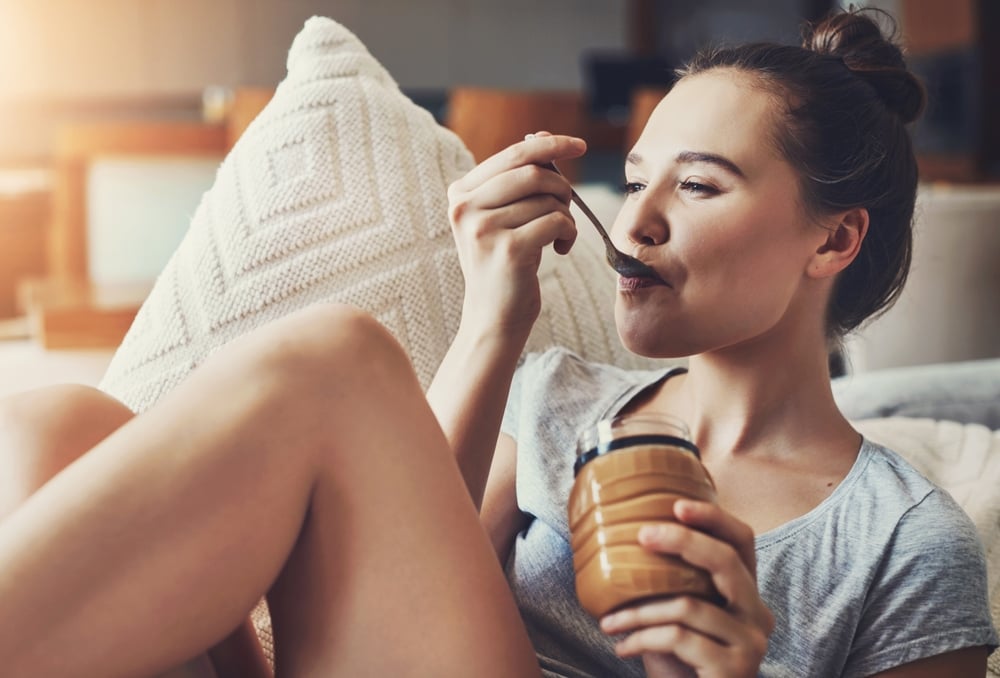 woman smiling eating from a jar