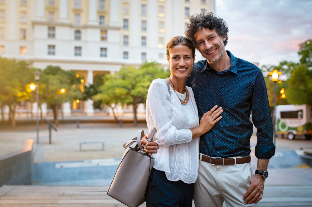 A smiling mature couple standing on the street and posing for a picture