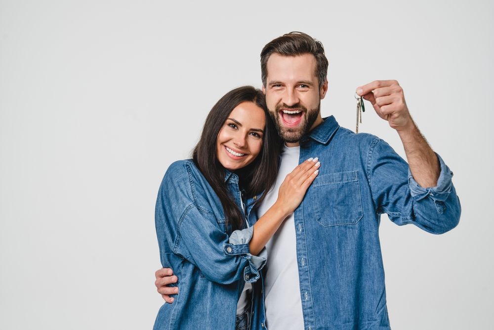 Happy couple wearing matching denim with the keys to their new place.