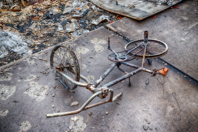 Childs bike lays on the ground everything destroyed by fire.