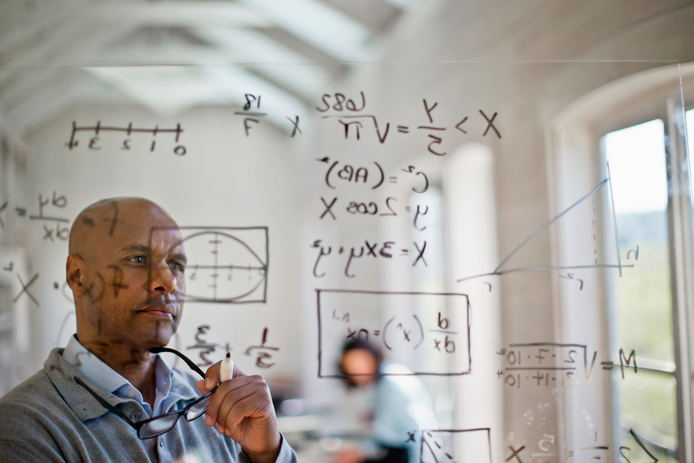 Mathematician working to solve mathematics equation on the board