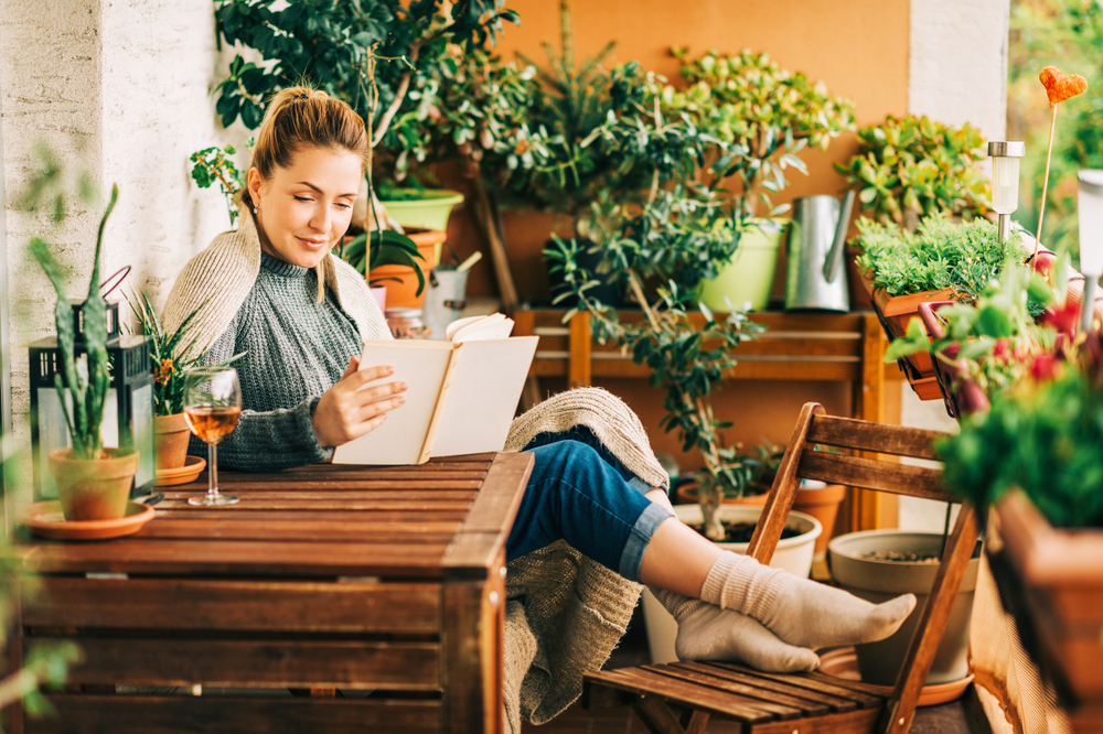 A woman relaxing and reading a book in her back balcony