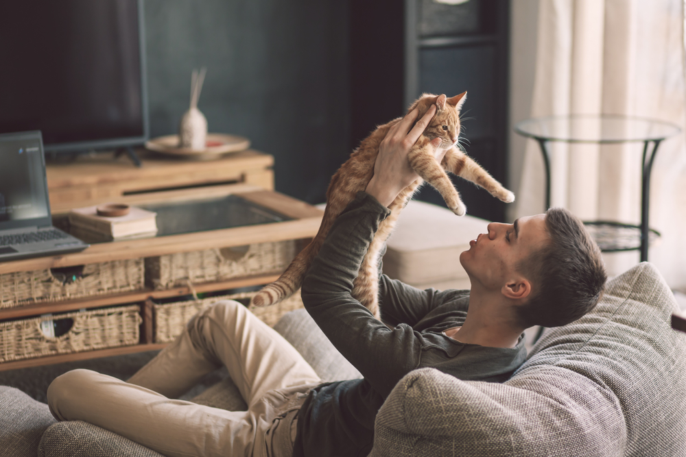 A man at home alone spending time with his kitten.