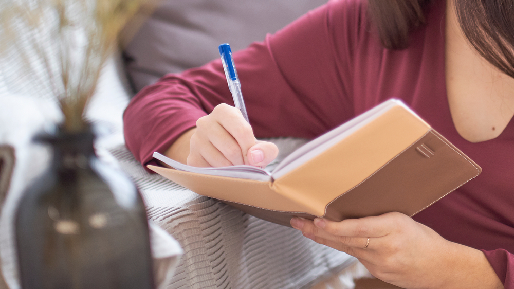 A young woman writing in her notepad