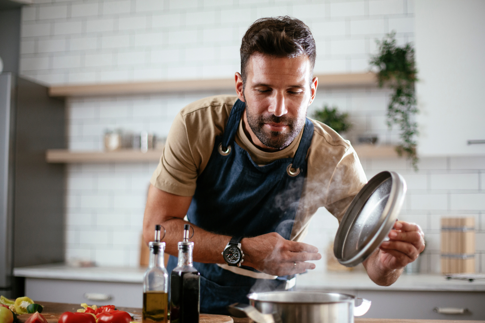 A happy mature man cooking in the kitchen