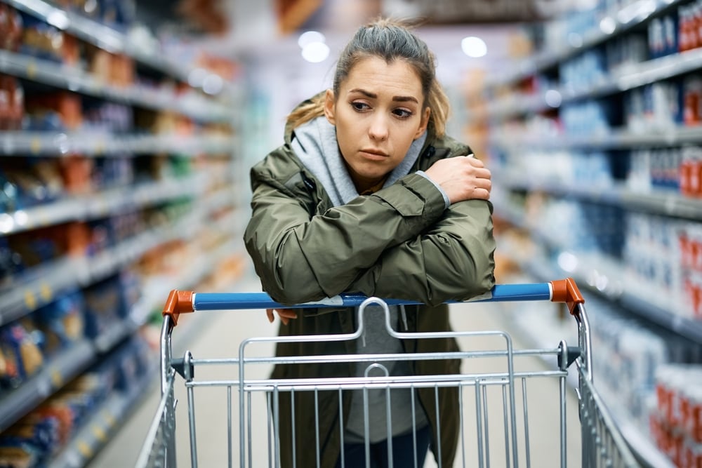 A young worried woman shopping for groceries