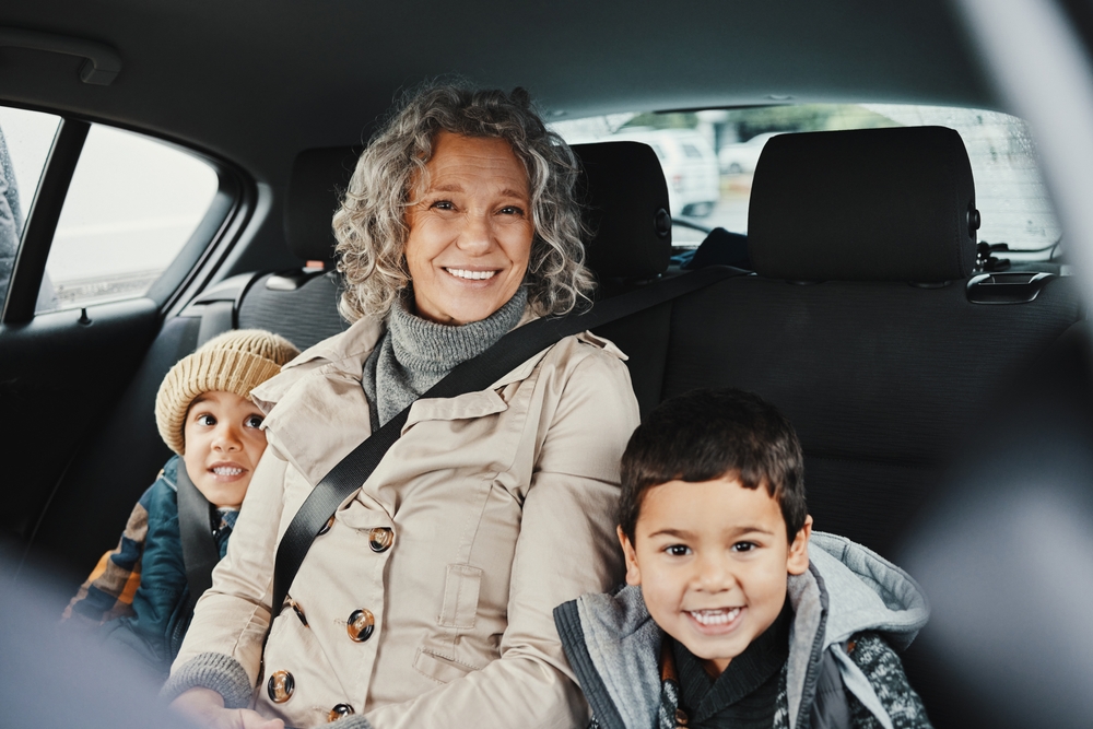 An elderly grandmother relax in car with her two grandchildren