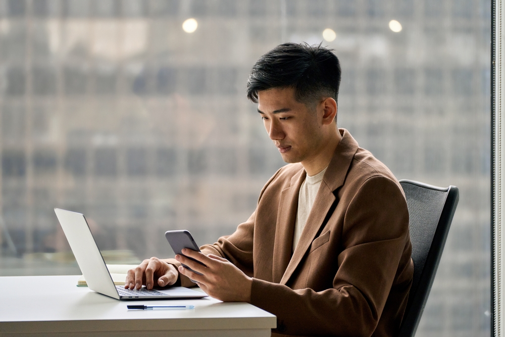 A busy smart and young business man working on his laptop and phone