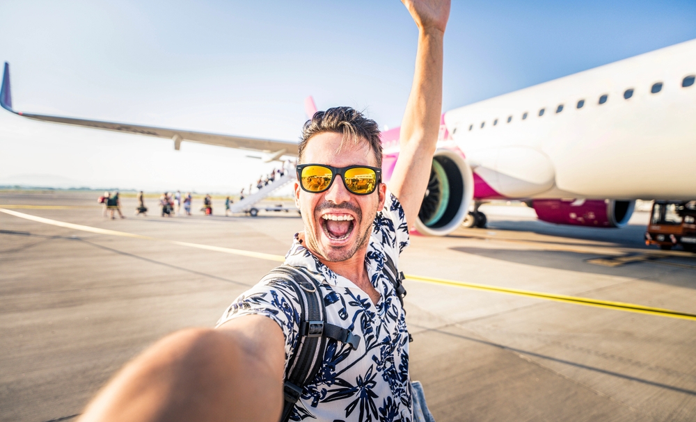 A happy young man about to get on a flight and travel for his vacation