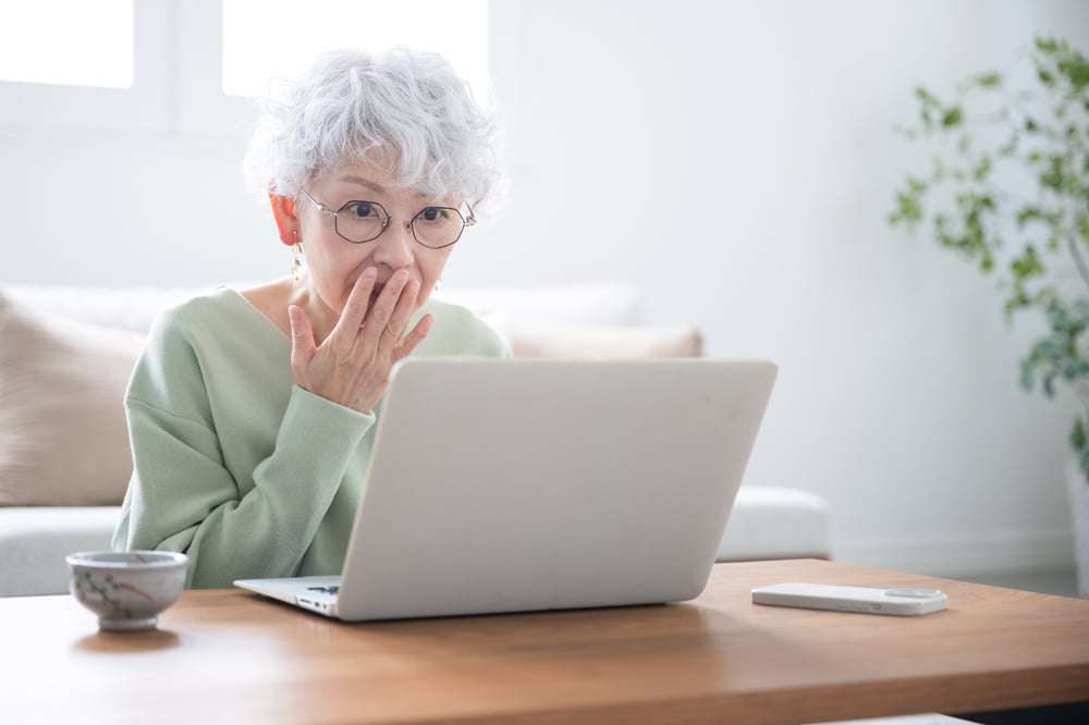 A surprised senior woman working on her laptop