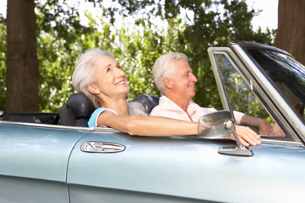 A senior couple in a sports car having fun and laughing