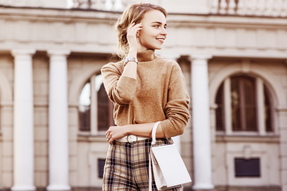 A fashionable young woman standing outdoors and smiling