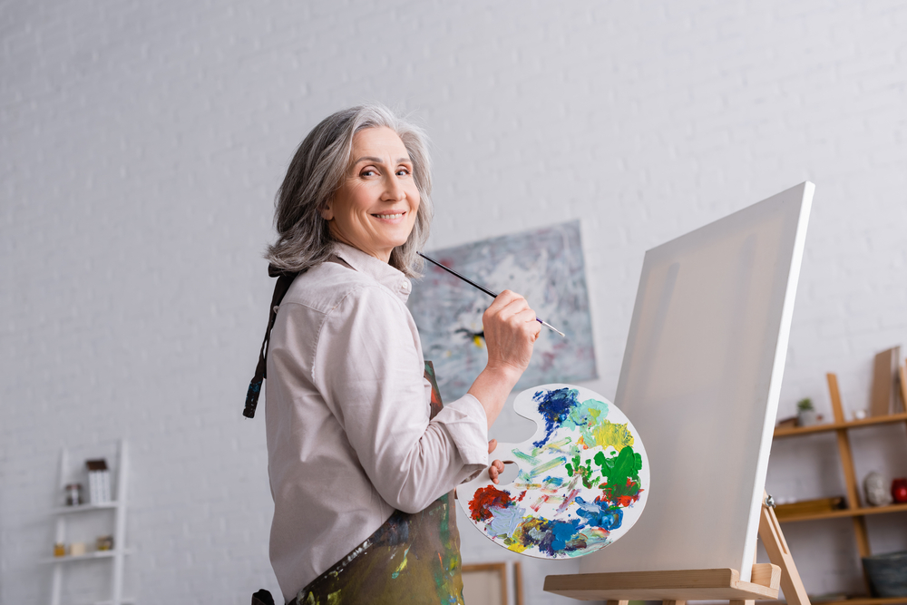 A cheerful middle aged woman painting