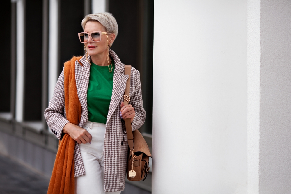 A fashionable older mature woman carrying a bag and wearing sunglasses