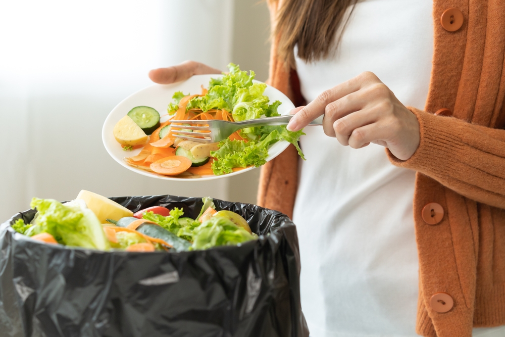 Woman scraping salad into the trash