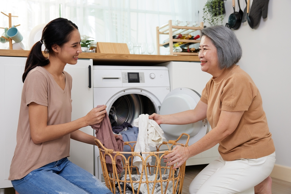 Senior mother and young daughter doing laundry together