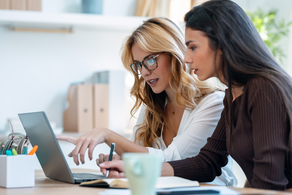 Two young attractive and elegant female colleagues working together