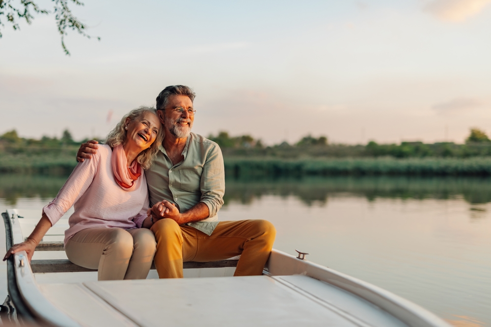 An elderly couple sitting by the waterside, having fun and enjoying their alone time