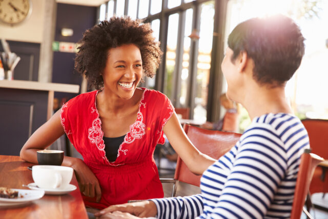 Two middle aged women looking at each other, talking and sharing a laugh