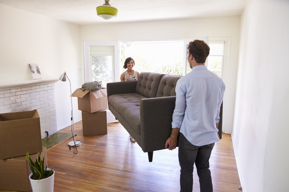 A couple moving into a new house and carrying in the couch or sofa
