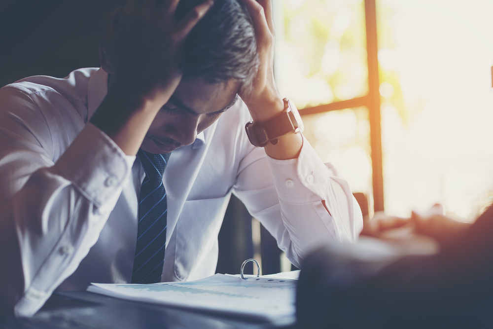 A tired business man resting his head on his hands