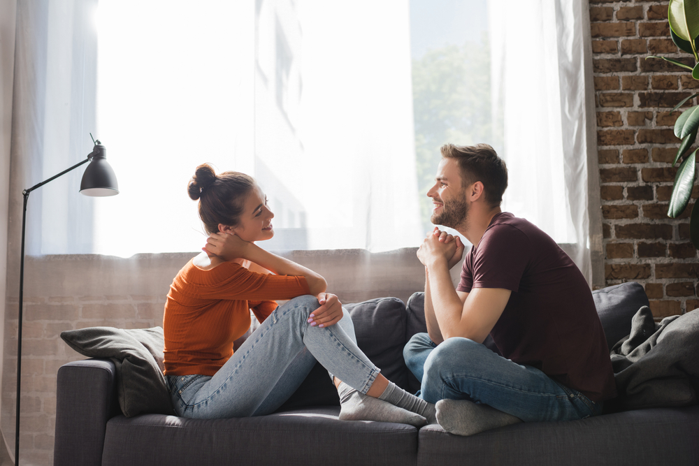A young couple sitting on the sofa and having a heartfelt conversation